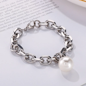Detail view of bold silver chain bracelet featuring a large round shell pearl pendant