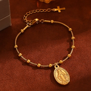 Macro shot of gold stainless steel bead bracelet with Mary medal and cross charm