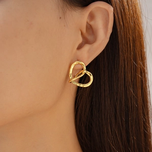 Close-up of a textured 18k gold plated heart earring on a model's ear with hammered finish