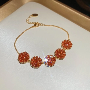 Close-up of 18k gold-plated bracelet featuring orange zircon flowers and lobster clasp