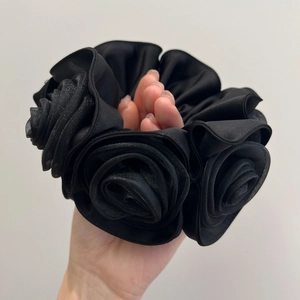Detailed view of a black satin and mesh scrunchie with layered rose flower design