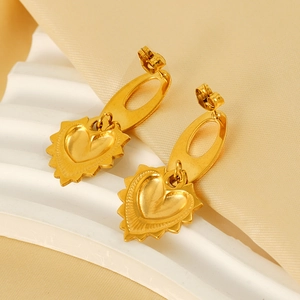 Élégantes boucles d'oreilles cœur en acier titane doré sur un socle blanc moderne