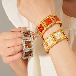Detail of vintage square enamel bracelet featuring gold, red, and brown spiral textures