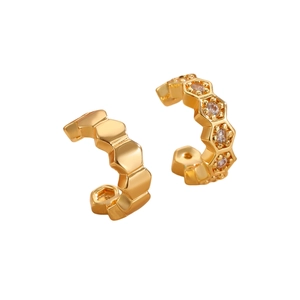 Elegantes pendientes hexagonales dorados con circonitas sobre un fondo blanco