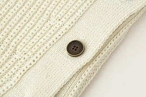 Detailed close-up of textured knit fabric with a vintage bronze metal button detail