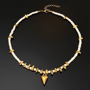 Detail der Perlenkette mit weißen Perlen, goldenen Elementen und Herzanhänger