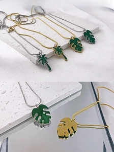 Détail de pendentifs feuille et palmier en émail vert sur une surface en pierre