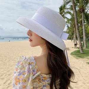 White wide brim straw hat with elegant silk bow ribbon detail for sun protection