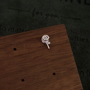 Macro shot of silver lollipop earring with pink inlay and zircon on a wooden stand