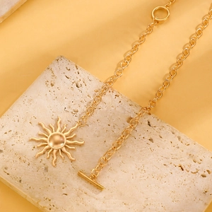 Dettaglio della collana con ciondolo a sole dorato e chiusura a T su pietra decor