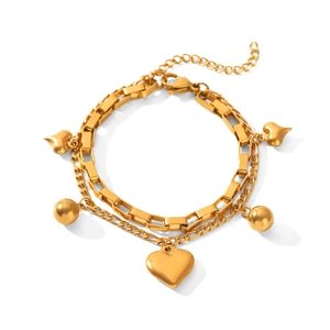 Vista de detalle de pulsera dorada de doble capa con dijes de corazón y cierre de mosquetón