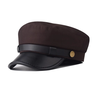 Detailed view of brown fabric sailor cap with black leather brim and vintage gold button