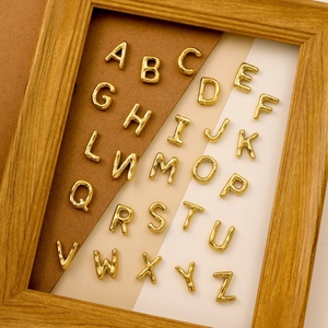 Close-up of golden A-Z bubble letter pendants made of polished stainless steel