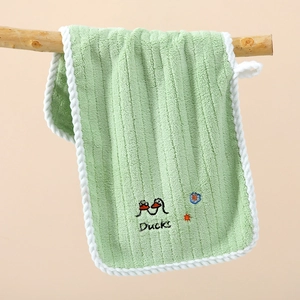 Soft striped coral velvet children hand towel in light green hanging on a branch