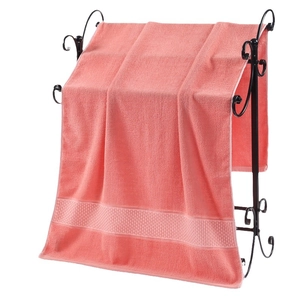 Pink pure cotton bath towel with soft loop texture hanging on a black metal rack