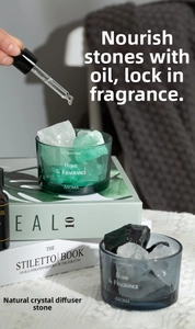 Applying essential oil with a dropper onto natural crystal stones in a green glass jar