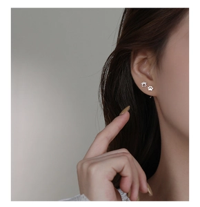 Close-up of minimalist silver cat paw earrings with zircons worn on a female model