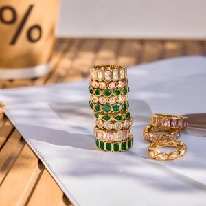 Macro shot of gold rings with colorful emerald, pink, and white zircon gemstones