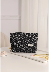 Detail of leopard jacquard makeup bag on elegant tray with golden brushes and pink flower