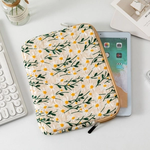 Detail of embroidered daisy patterns on a quilted off-white laptop sleeve with zipper