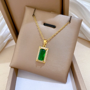 Macro detail of gold-plated titanium necklace featuring a green stone and crystal halo