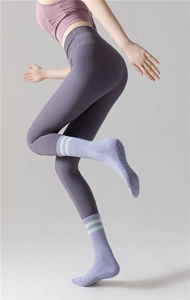 Détail de chaussettes de yoga violettes avec picots antidérapants et revers rayés verts