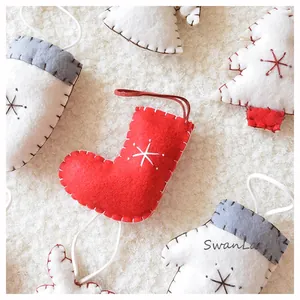 Detail of handmade felt Christmas ornaments with star embroidery on white faux fur background