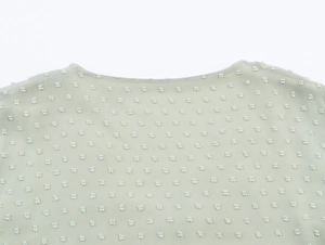 Vue détaillée du col en V d'une robe en mousseline vert clair à texture floquée douce