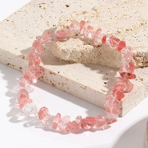 Macro detail of natural pink strawberry quartz beaded stretch bracelet on stone tiles