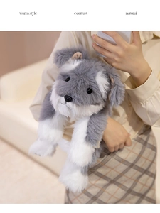 Close-up of lifelike gray and white Schnauzer plush toy held by hands in a warm home setting
