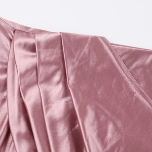 Detail of elegant dusty pink satin dress showing sleek pleats and fine stitching craftsmanship