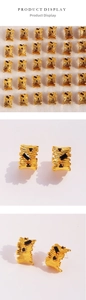 Macro shot of gold-plated textured metal earrings with black zircon stones