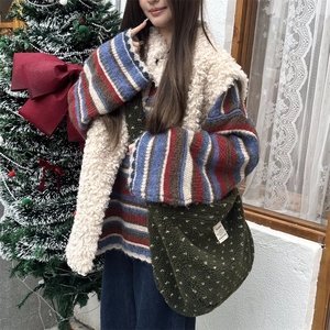 Detail of dark green plush crossbody bag styled with warm winter layers and festive decor