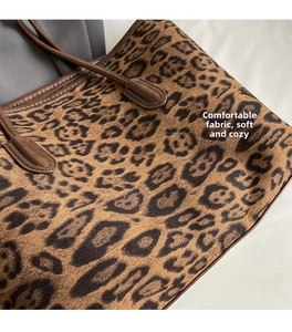 Close-up of leopard print tote bag showing soft velvet texture and leather handle stitching