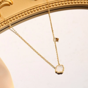 Vintage 18K gold plated heart shell necklace on a mirror with soft golden reflections
