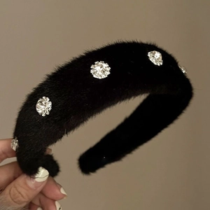 Close-up of black plush headband with sparkling crystal floral ornaments and soft texture