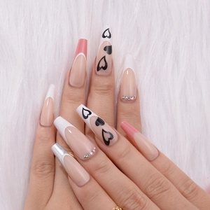 Close-up of long coffin and almond press-on nails with French tips and rhinestones