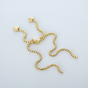 Detail of gold snake chain bracelet featuring a CZ pavé slide clasp and heart charms