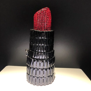 Detail shot of a lipstick-shaped clutch bag with red crystals and black rhinestones