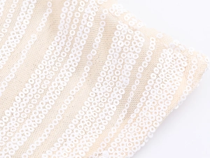 Close-up of white sequins on beige mesh fabric showing detailed stripe pattern texture