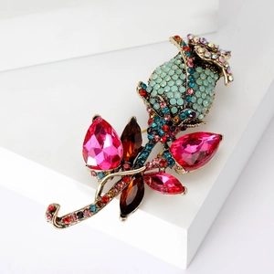 Elegant gold-tone rose brooch set with blue and multicolored crystals on a pedestal