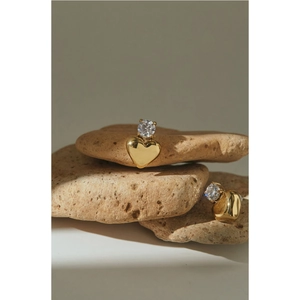 Elegant gold heart earrings with sparkling zircon on natural stone background