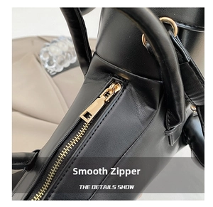 Detail of smooth gold metal zipper on black lychee textured leather tote bag