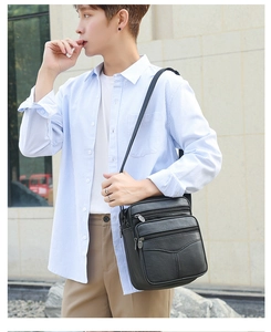 Outdoor shot of a black multi-zipper leather messenger bag worn over the shoulder