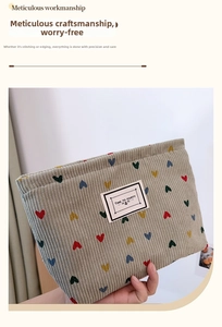 Detail of beige corduroy cosmetic bag featuring colorful heart embroidery and text patch