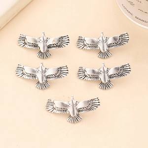 Retro silver eagle alloy hair ring charms for dreadlocks and braids on a beige background