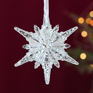 Transparent acrylic snowflake ornament with colorful glitter on a festive red background