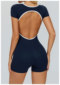Detail of cross-back cutout and white trim on a navy blue athletic yoga jumpsuit