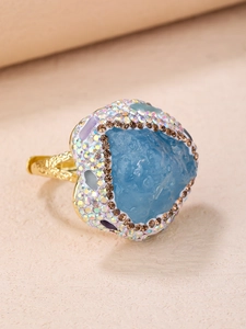 Vue macro détaillée d'une bague en pierre bleue en forme de cœur irrégulier et pavé arc-en-ciel