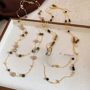 Detail of vintage tiger eye beaded necklaces layered over elegant textured fabrics
